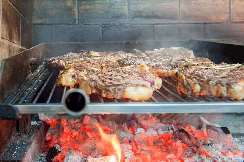 Parrilla repleta de txuletas cocinándose sobre las brasas